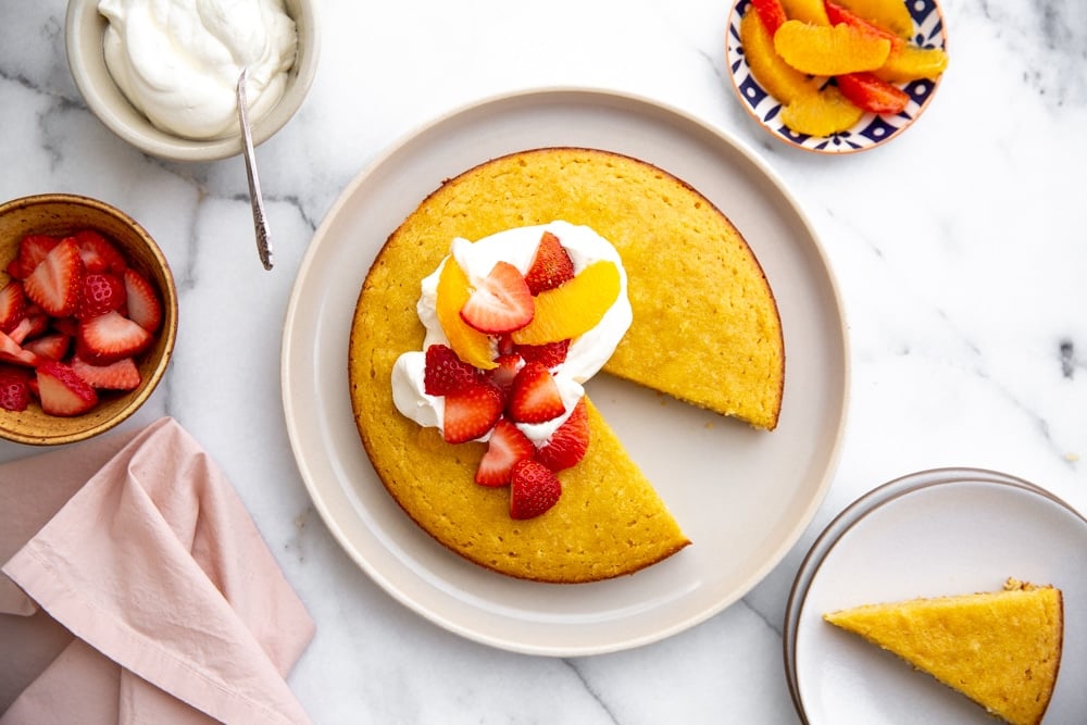 Overhead shot of the almond coconut cake topped with whipped cream and fruit.