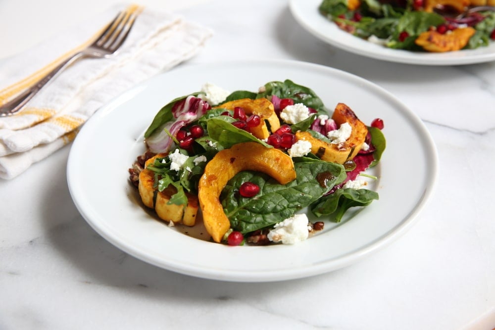 Roasted squash salad on a plate with fork in the background.