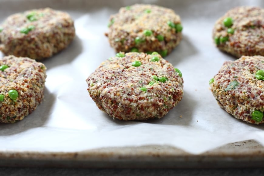 Process shot showing uncooked quinoa burger patties lined up on baking sheet.