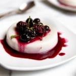 Vegan panna cotta on plate, topped with roasted berries