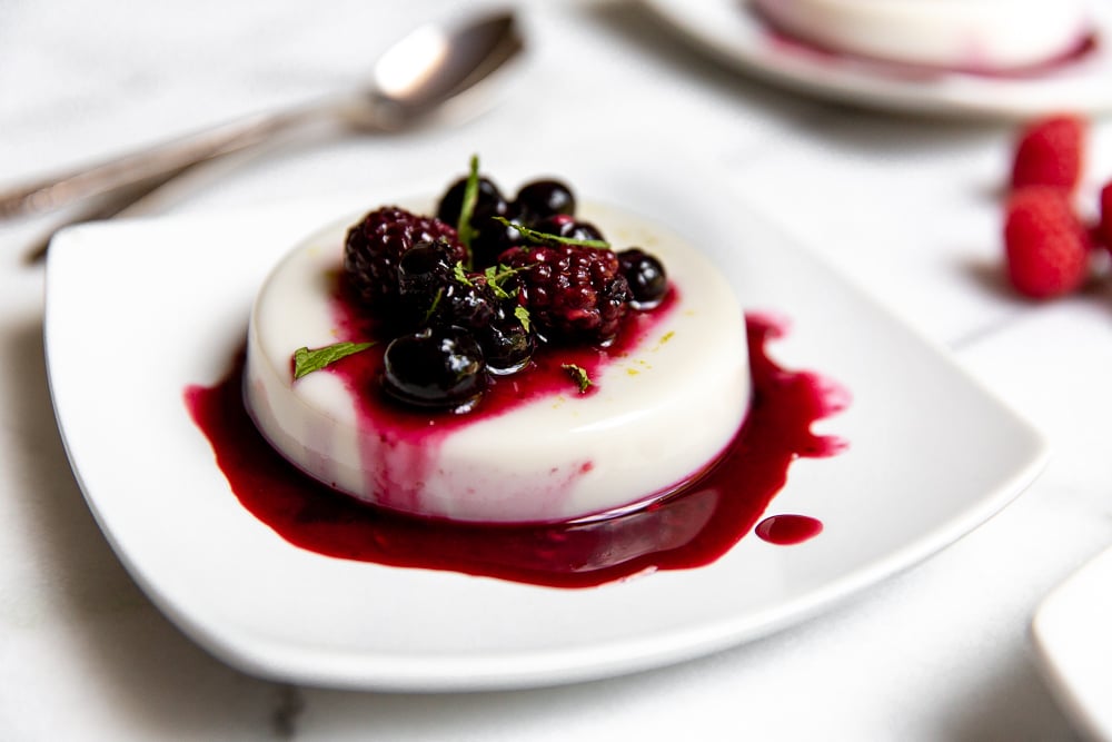 Vegan panna cotta on plate, topped with roasted berries