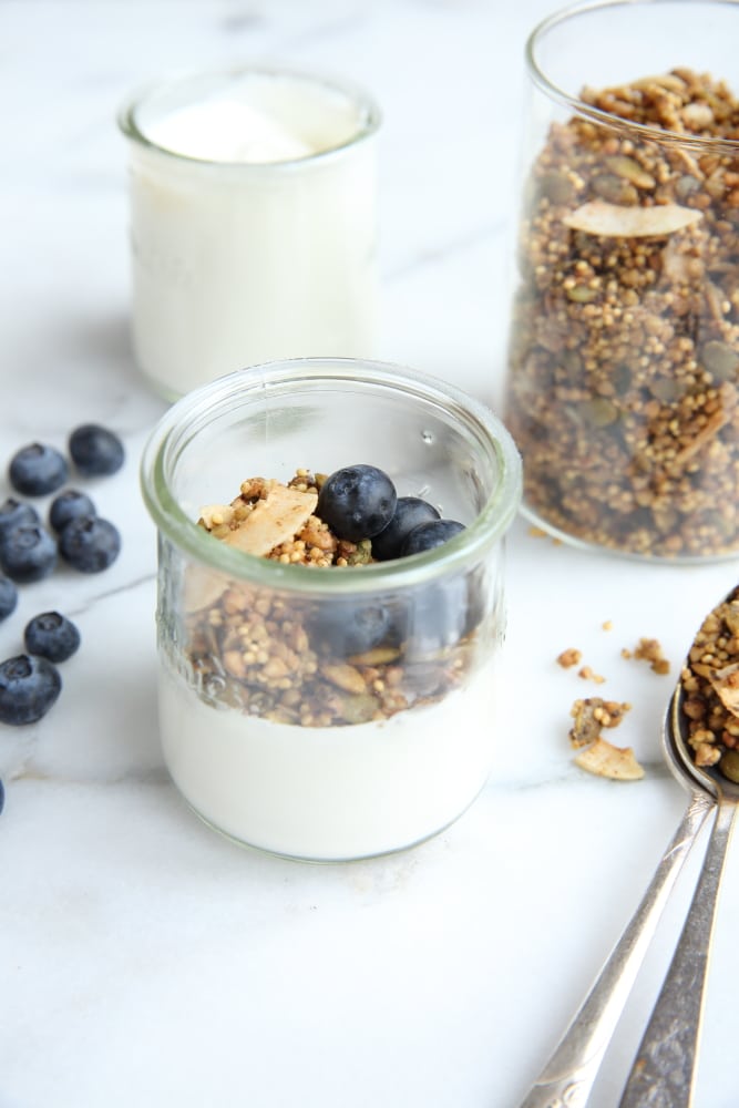 Side angle shot of millet granola in jar with yogurt with blueberries