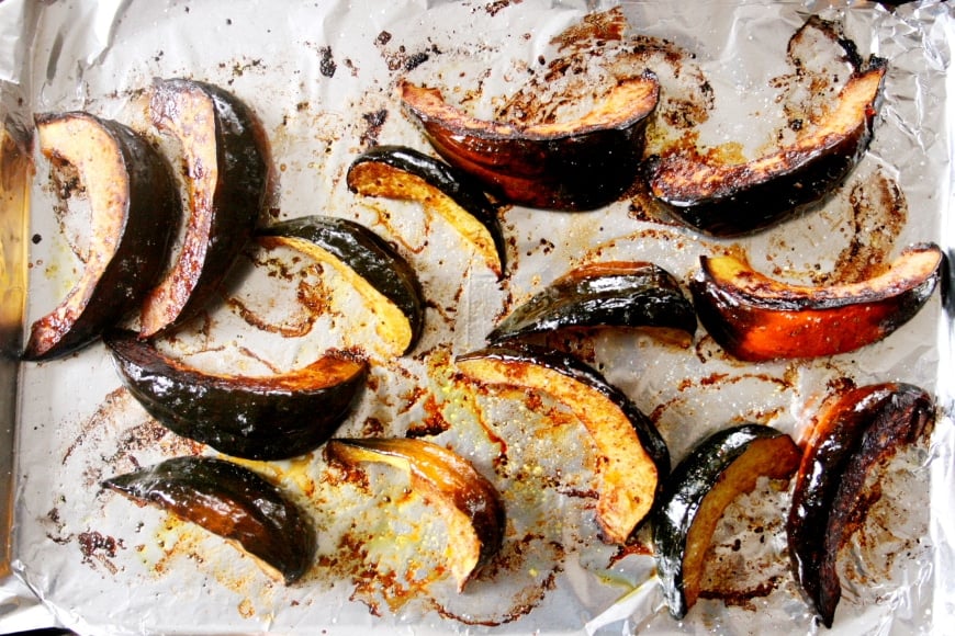 Process shot showing the cooked acorn squash wedges on a baking sheet.