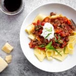 Lamb ragu with Papperdelle in bowl with cheese and wine on the side