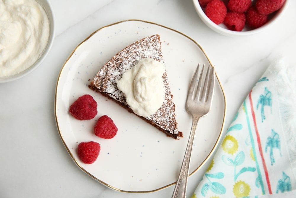 Chocolate cake on plate with whipped cream and raspberries