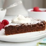 gluten free chocolate almond cake on plate with whipped cream