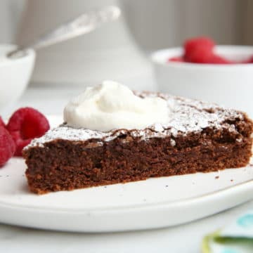gluten free chocolate almond cake on plate with whipped cream