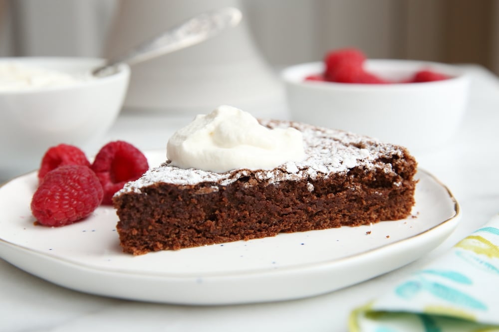 gluten free chocolate almond cake on plate with whipped cream