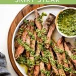 Grilled skirt steak on a serving platter drizzled with salsa verde.