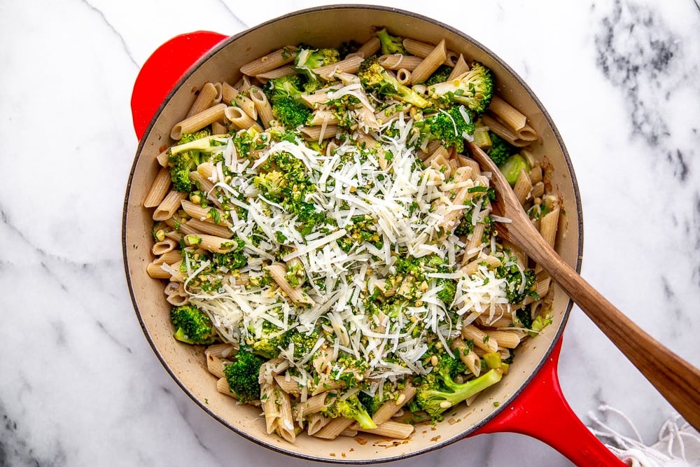 Broccoli pasta in a large skillet with a wooden spoon.