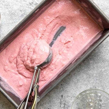 Strawberry frozen yogurt in loaf pan with ice cream scoop.