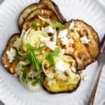 Grilled eggplant salad on a plate topped with feta cheese and mint.