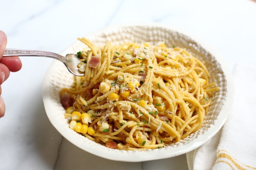 Close up of fork twirling spaghetti with corn and bacon. 