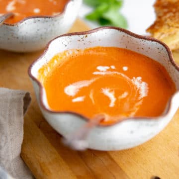 Bowl of Vitamix tomato soup on a wooden serving board.