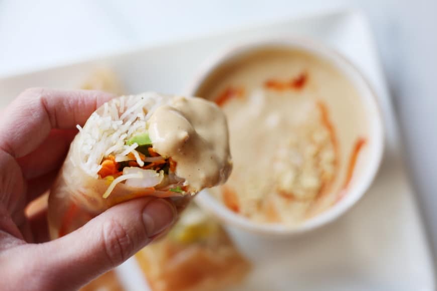 Close-up of a winter roll dipped in peanut sauce. 