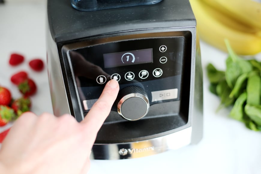 Finger pressing the "on" button on the Vitamix blender 