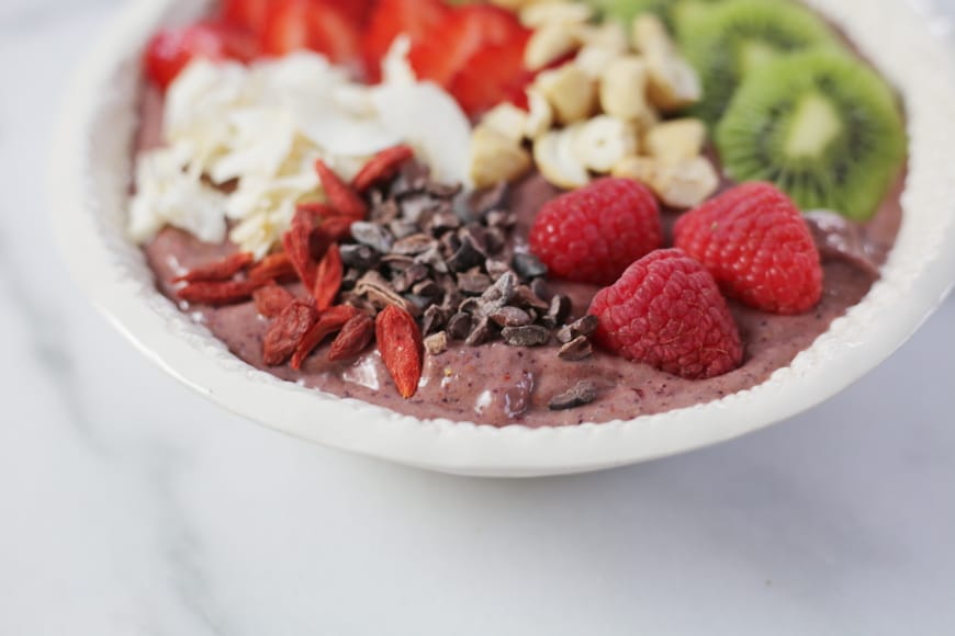Superfood berry smoothie bowl topped with berries, cacao nibs, nuts and coconut