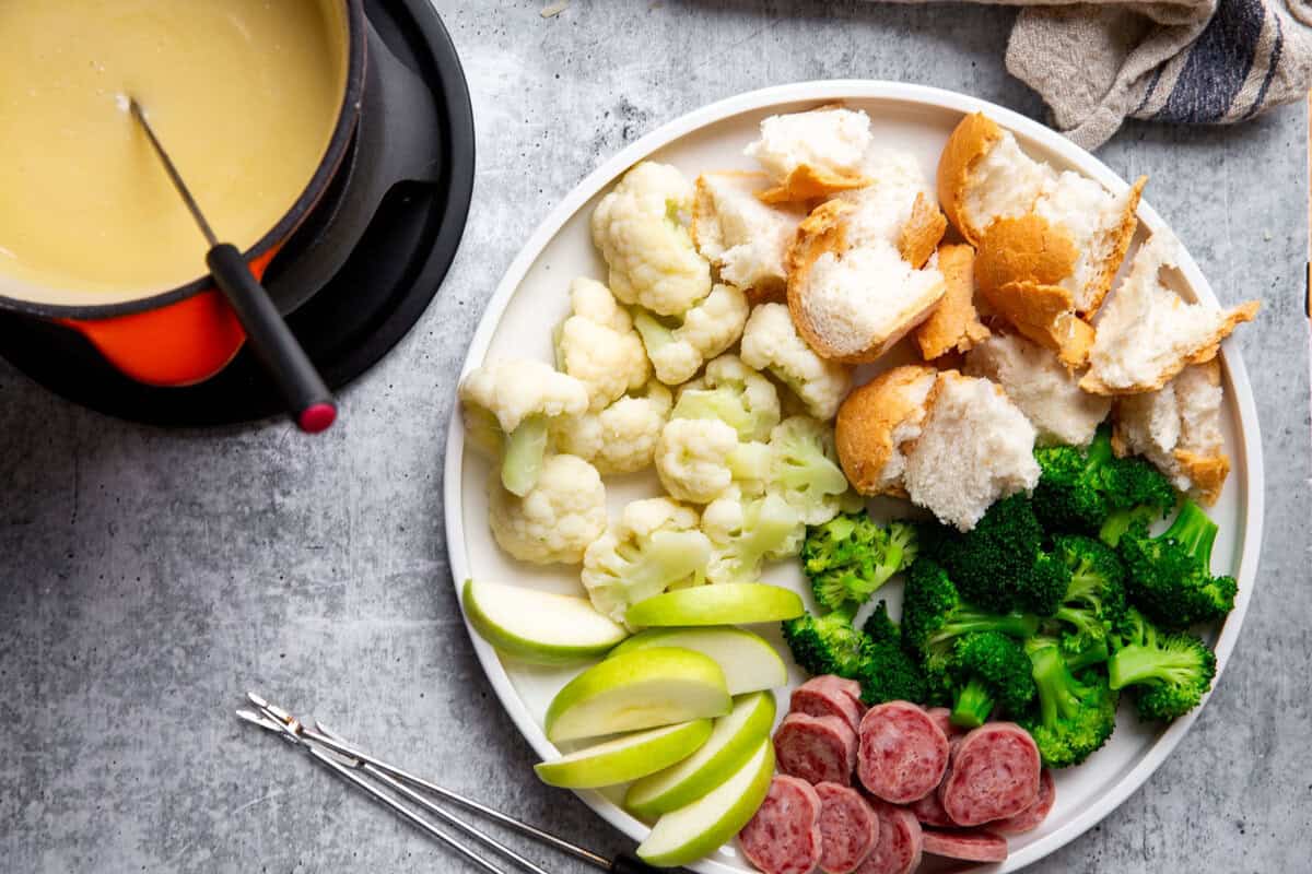 a plate of dippers for next to a bowl of cheese fondue