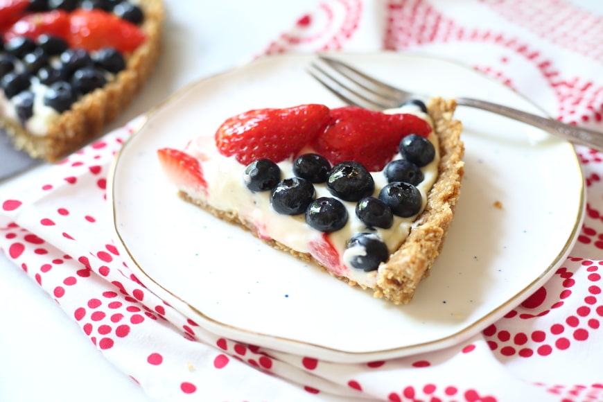 Slice of gluten free berry tart on plate with fork. 