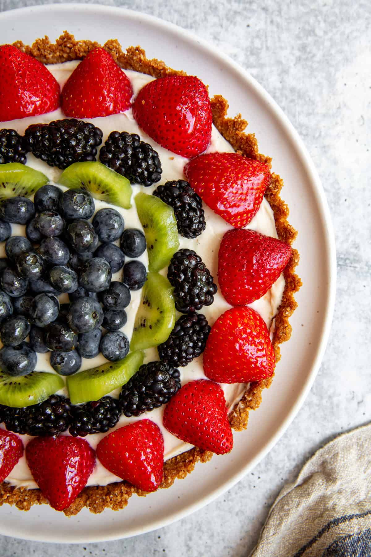 a top view of half of the gluten-free tart topped with berries and kiwi.
