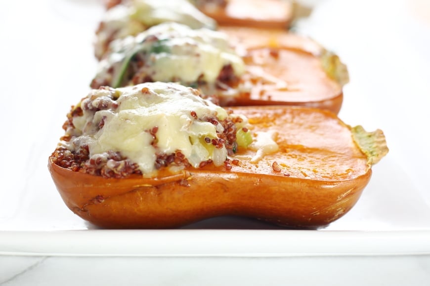 Close up side view of a stuffed honeynut squash with melted cheese.