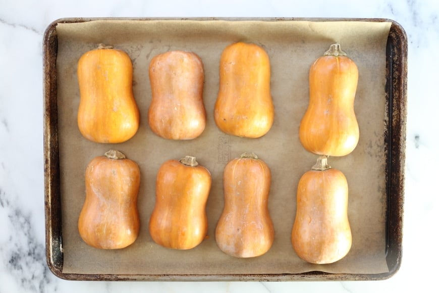 Halved honeynut squash lined up on a baking sheet