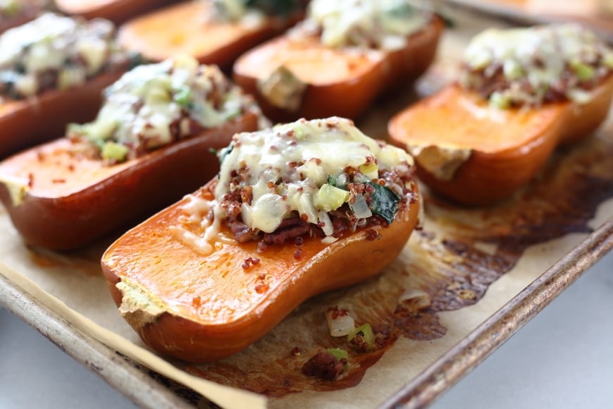 Close up of a stuffed honeynut squash on a baking sheet.