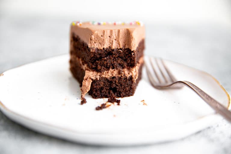 Close up of a slice of chocolate quinoa cake with chocolate whipped cream frosting, with a bite removed.