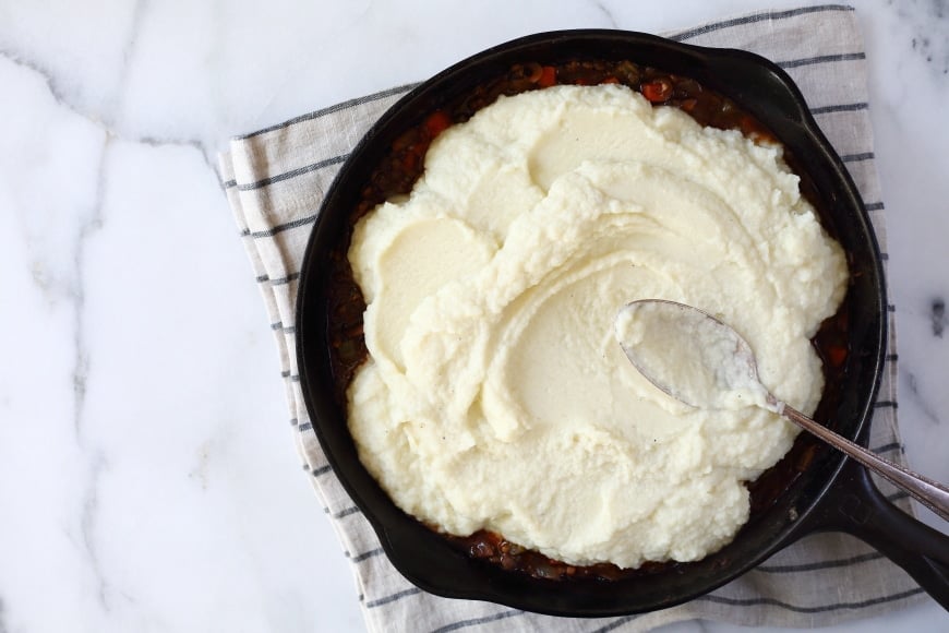 Uncooked lentil shepherds pie in cast iron skillet