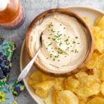 Sriracha cream cheese dip in a bowl with potato chips alongside.
