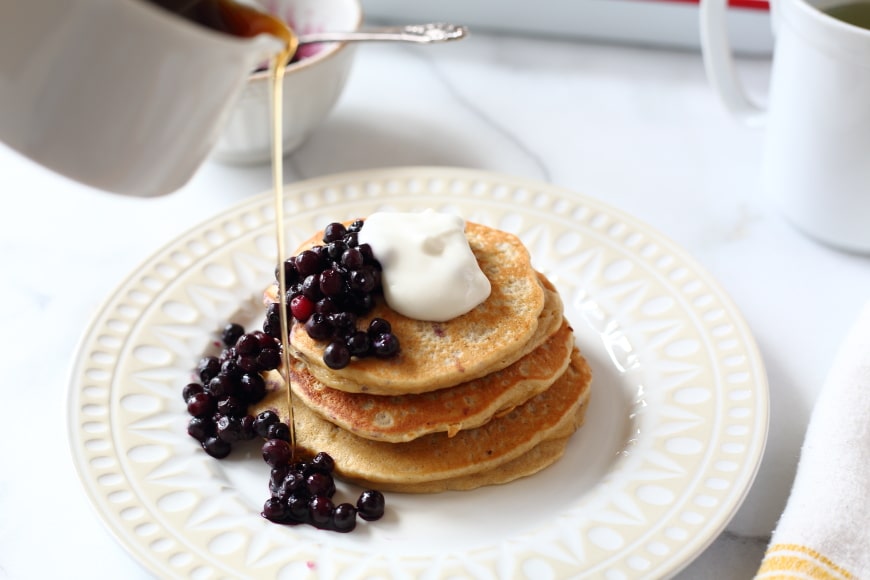 Banana oat blender pancakes on plate with syrup and berries