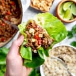 Close-up of a hand holding a healthy Asian beef lettuce wrap.