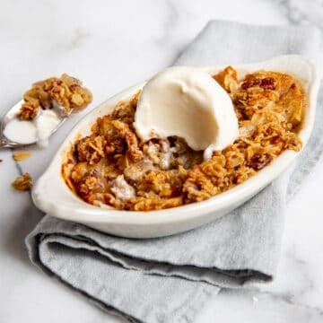 Healthy gluten free apple crisp in a small dish topped with vanilla ice cream.