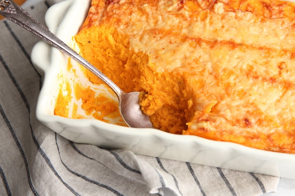 Gluten free sweet potato souffle casserole with a serving spoon. 