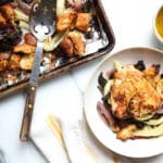 Sheet pan chicken thighs on plate with warm panzanella salad and sheet pan in background