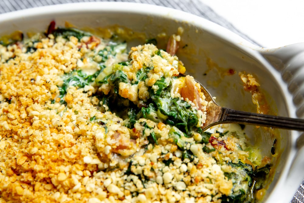 Close up of a spoon scooping up a serving of Swiss chard gratin.