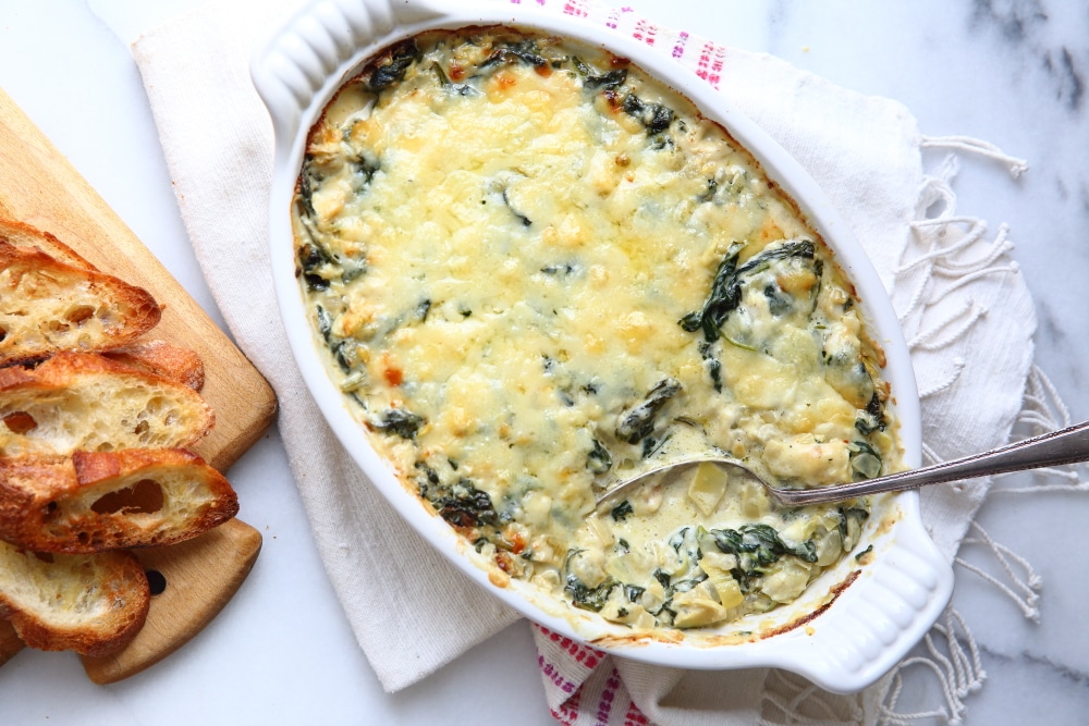Warm spinach and artichoke dip on a marble surface.