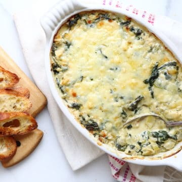 Warm spinach and artichoke dip in baking dish with bread on the side