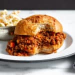 A healthy sloppy joes sandwich on a plate with a bite taken out.