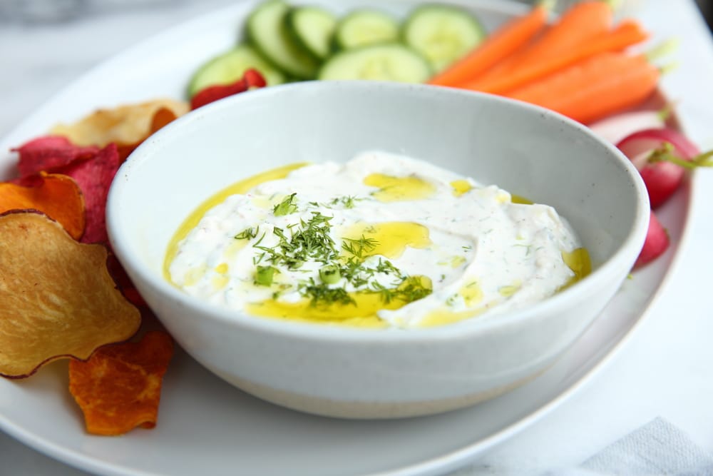 Greek yogurt feta dip in bowl with chips and veggies alongside