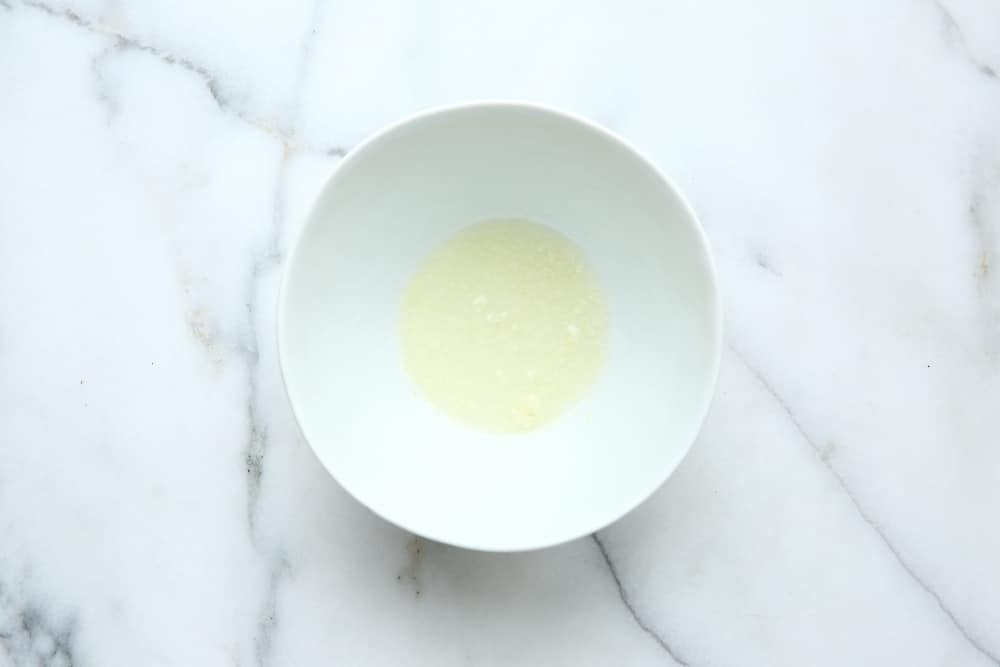 Process shot showing lemon juice and garlic in bowl