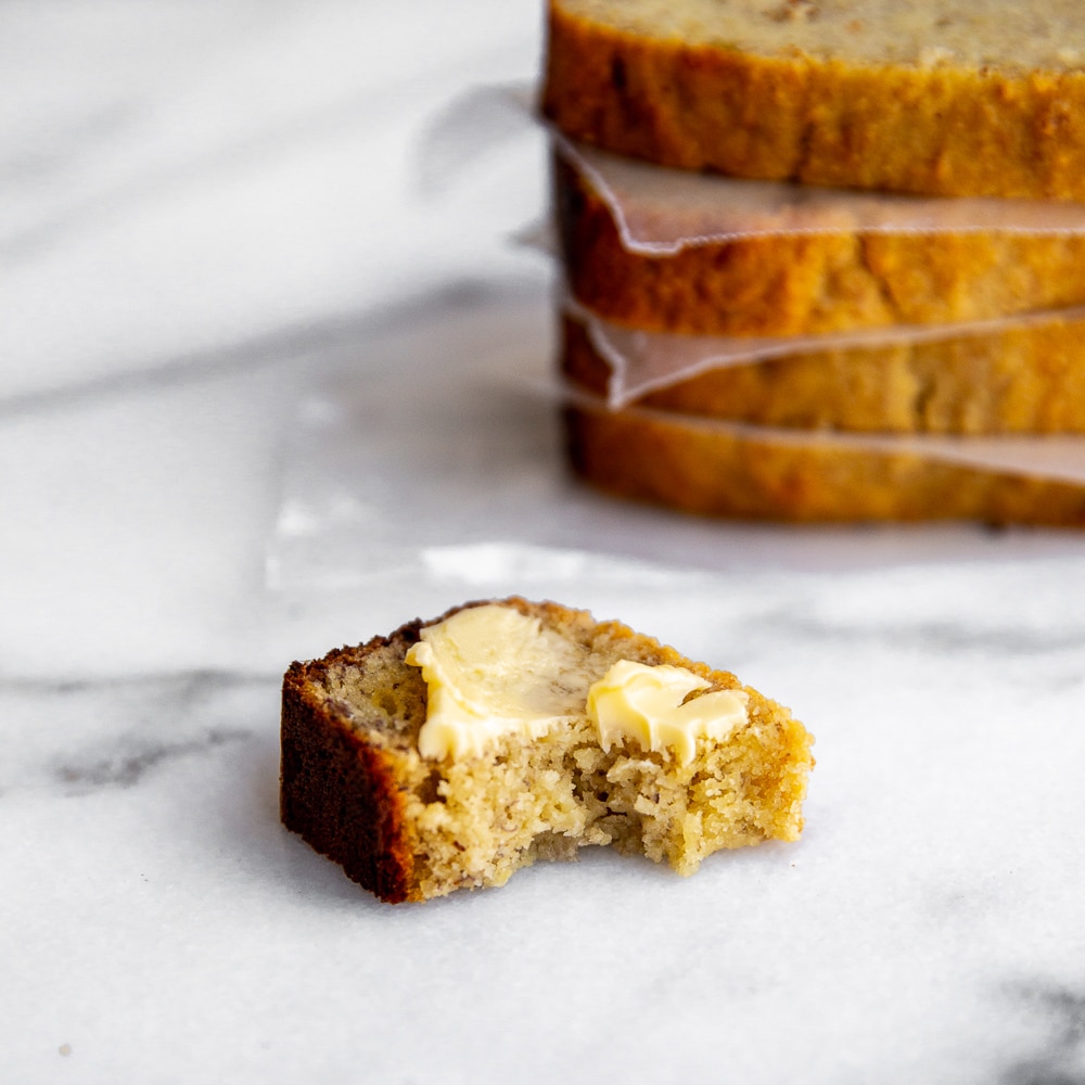 Close up of a buttered slice of paleo banana bread with bite taken out.