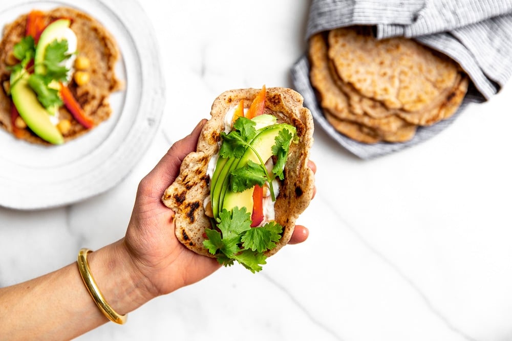 Taco in a hand with a stack of cassava tortillas in the background