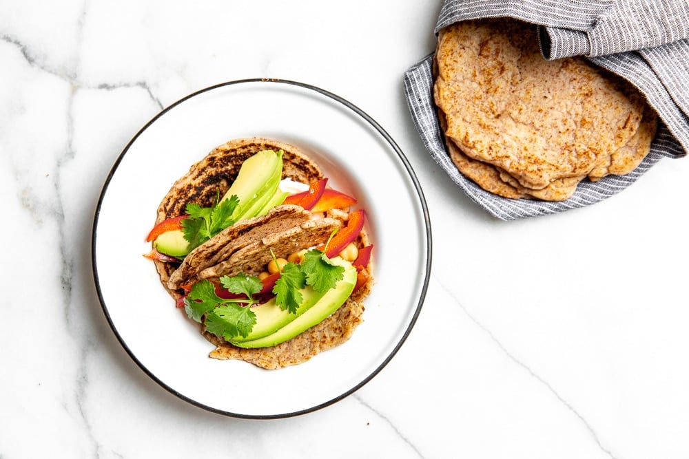 Vegetable tacos on a plate made with cassava tortillas, with a stack of tortillas on the side. 