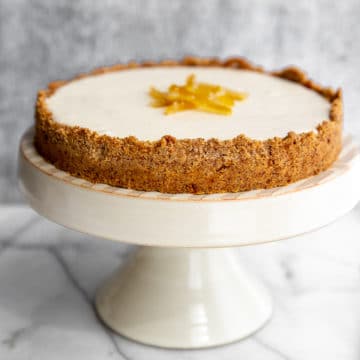 Creamy lemon pie with almond crust on cake stand with pie server on the side