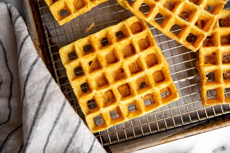 Chickpea waffles lined up on cooling rack set over sheet pan