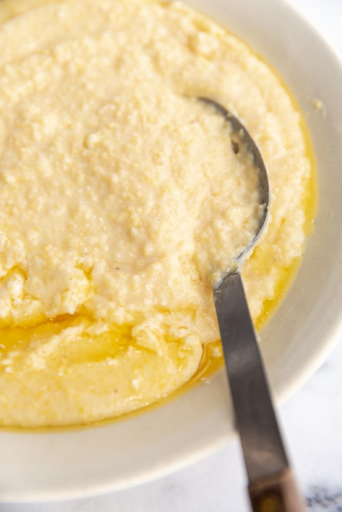 Creamy grits in a bowl with a serving spoon