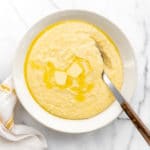 Creamy grits from scratch in serving bowl with serving spoon