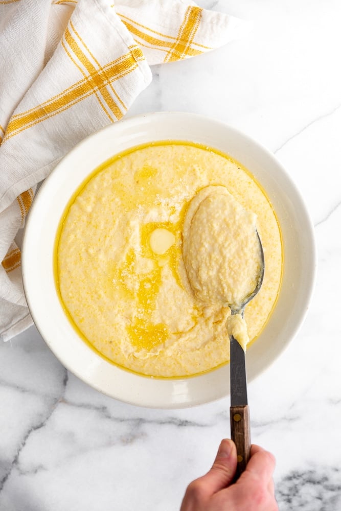 Creamy grits from scratch in a serving bowl with a serving spoon