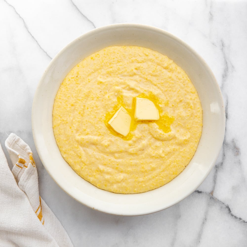 Creamy grits from scratch in a serving bowl with a serving spoon